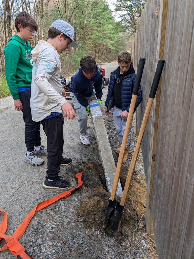 Photo of boy scouts installing a granite post with mile markers.